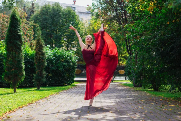 Kvinna ballerina i röd balett klänning dans i pointe skor i höstparken. — Stockfoto