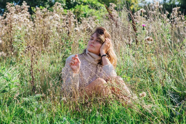 Felice giovane bella donna in maglione e mutande seduta a piedi nudi in un campo di agrimonia secca — Foto Stock