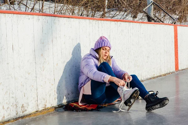 Belle jeune femme assise sur un anneau de glace et attachant lacets — Photo