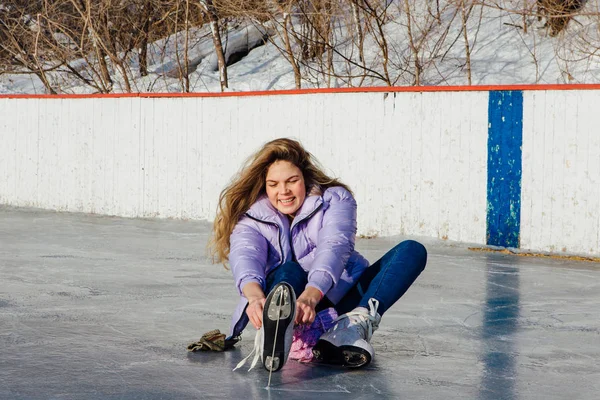 Preciosa joven sentada en un anillo de hielo y atando cordones — Foto de Stock