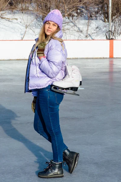 Прекрасна молода жінка з ковзанами, що звисають на шиї на ковзанці . — стокове фото