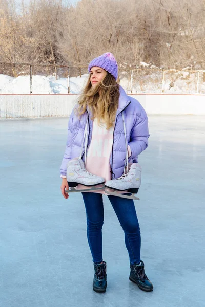 Belle jeune femme avec des patins à glace suspendus sur le cou sur la patinoire . — Photo