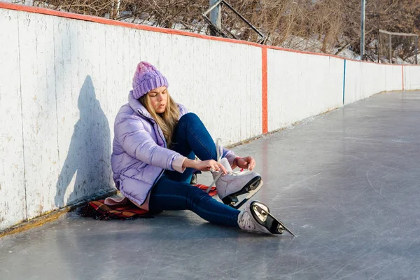 Belle jeune femme assise sur un anneau de glace et attachant lacets — Photo