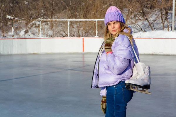 Belle jeune femme avec des patins à glace suspendus sur le cou sur la patinoire . — Photo