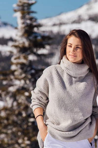 Retrato de uma jovem bela mulher morena com olhos azuis e sardas no rosto no inverno paisagem de montanha nevada. Menina bonita no inverno ao ar livre . — Fotografia de Stock