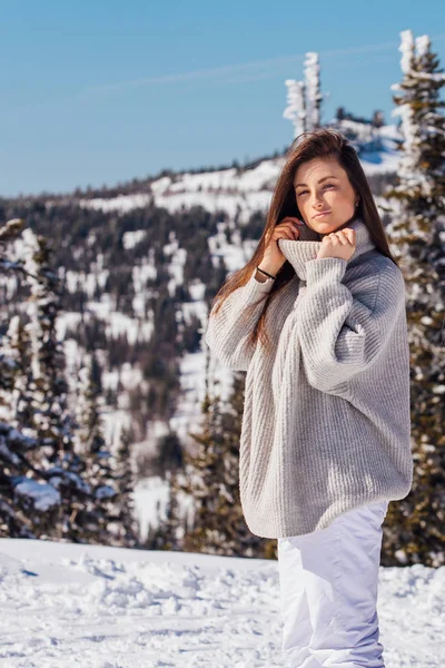 Retrato de uma jovem bela mulher morena com olhos azuis e sardas no rosto no inverno paisagem de montanha nevada. Menina bonita no inverno ao ar livre . — Fotografia de Stock