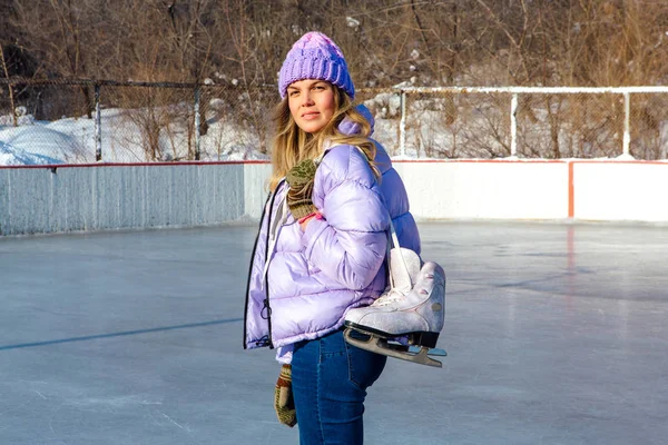 Belle jeune femme avec des patins à glace suspendus sur le cou sur la patinoire . — Photo