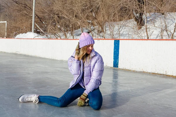Belle jeune femme assise sur la patinoire avec des patins à glace sur les pieds . — Photo