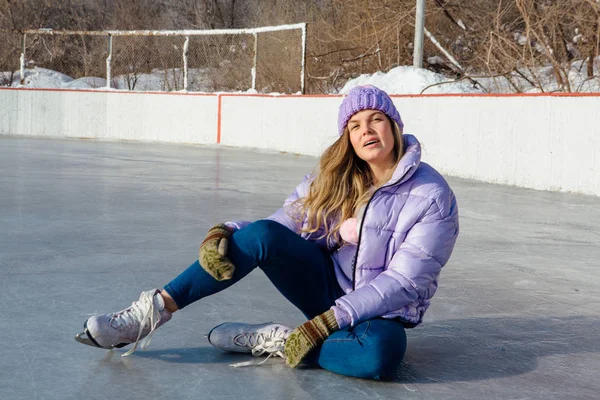 Buz patenleriyle buz pistinde oturan genç ve güzel bir kadın.. — Stok fotoğraf