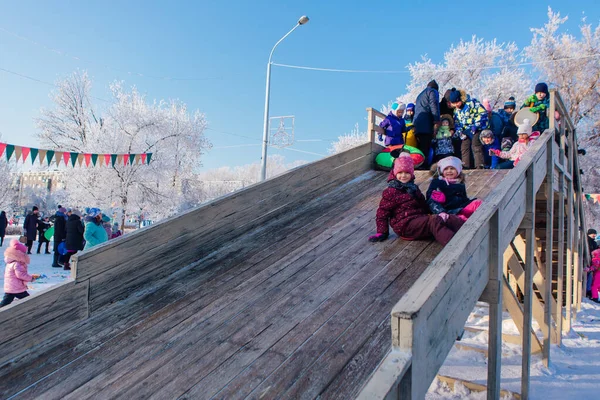 Novokuznetsk, russland - 07. Januar 2019: Russische Winterunterhaltung: Kinder beim Rodeln von der Holzrodelbahn — Stockfoto