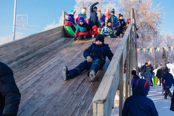 Novokuznetsk, russland - 07. Januar 2019: Russische Winterunterhaltung: Kinder beim Rodeln von der Holzrodelbahn — Stockfoto