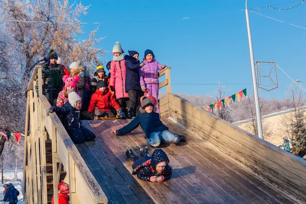 Novokuznetsk, russland - 07. Januar 2019: Russische Winterunterhaltung: Kinder beim Rodeln von der Holzrodelbahn — Stockfoto