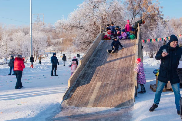 Novokuznetsk, russland - 07. Januar 2019: Russische Winterunterhaltung: Kinder beim Rodeln von der Holzrodelbahn — Stockfoto