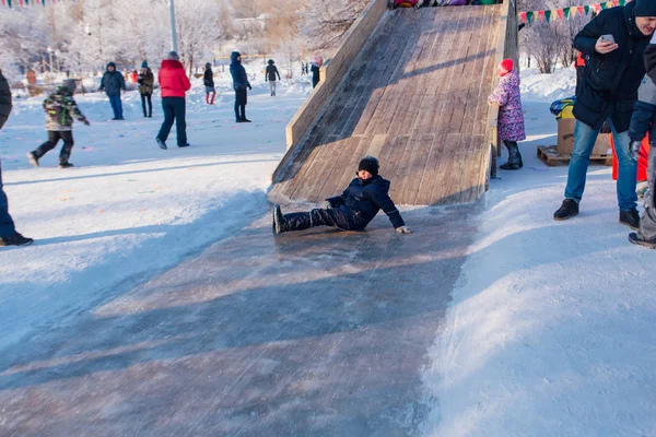 Novokuznetsk, russland - 07. Januar 2019: Russische Winterunterhaltung: Kinder beim Rodeln von der Holzrodelbahn — Stockfoto