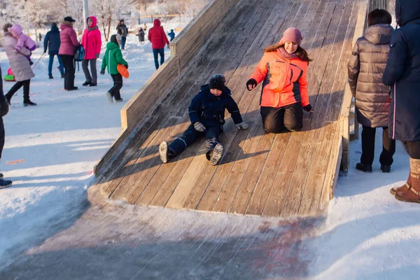 Novokuznetsk, russland - 07. Januar 2019: Russische Winterunterhaltung: Kinder beim Rodeln von der Holzrodelbahn — Stockfoto