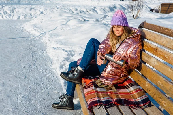 Jeune belle fille blonde assise sur un banc dans le parc d'hiver — Photo