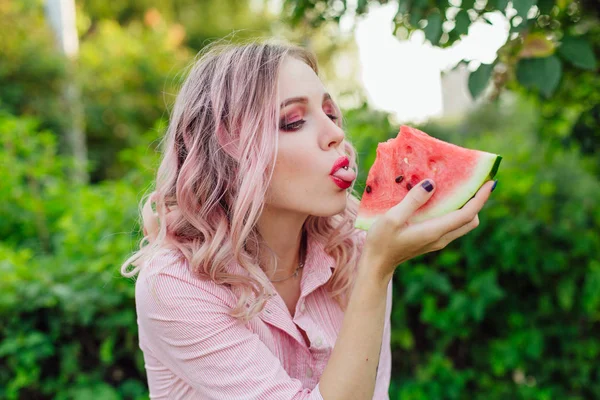 Beautiful young woman with pink hair enjoying watermelon — Stock Photo, Image