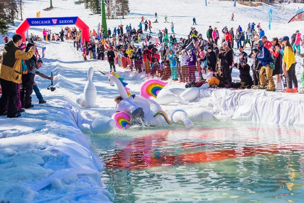 Sheregesh, kemerowo region, russland - 13. April 2019: pool and ride contest, bei dem Menschen auf einem Schwimmring auf dem schneebedeckten Hang neben dem Pool riesige Bowling spielen. — Stockfoto