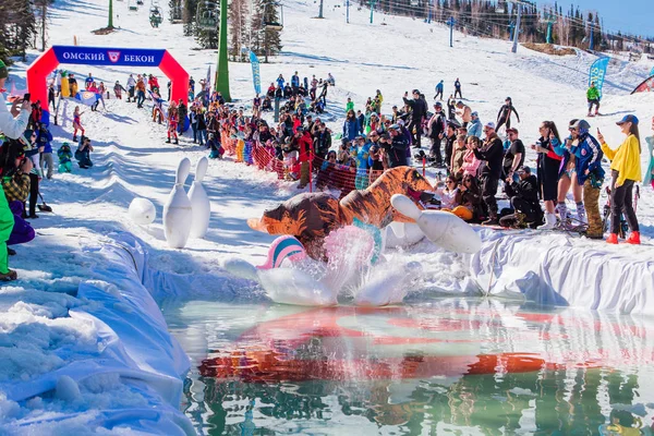 Sheregesh, Kemerovo bölgesi, Rusya - 13 Nisan 2019: Yüzme havuzunda insanların havuzun yanındaki karlı yamaçta büyük bowling oynadıkları yarışma. — Stok fotoğraf