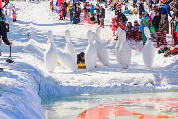 Sheregesh, kemerowo region, russland - 13. April 2019: pool and ride contest, bei dem Menschen auf einem Schwimmring auf dem schneebedeckten Hang neben dem Pool riesige Bowling spielen. — Stockfoto