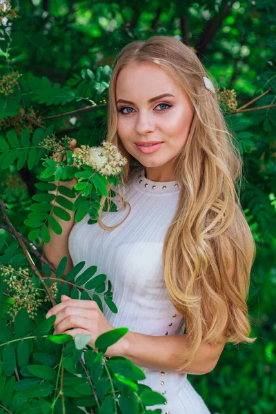 Portret van een charmante blonde vrouw het dragen van mooie witte jurk staande naast Rowan tree. — Stockfoto