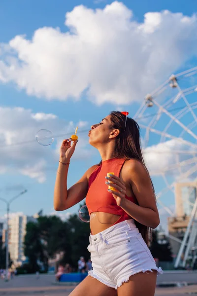 Vacker ung kvinna blåser såpbubblor utomhus — Stockfoto