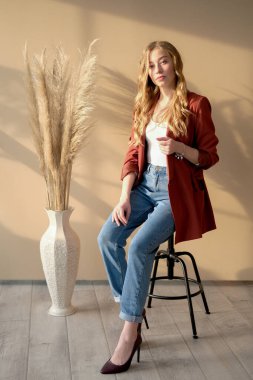 Genç, güzel, sarışın kadın. Pencereden gün ışığında bar sandalyesinde oturuyor.