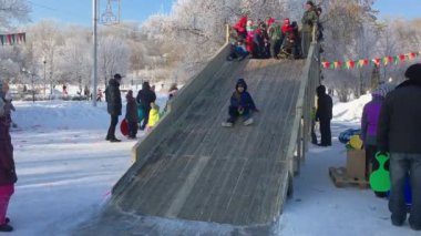 Novokuznetsk, Russia- January 07, 2019: Russian winter entertainment: children having fun tobogganing from wooden toboggan