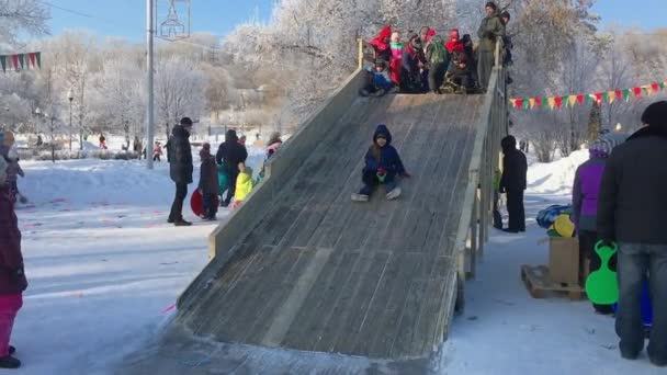 Novokuznetsk, Rusia- 07 de enero de 2019: Entretenimiento de invierno ruso: los niños se divierten bailando tobogán de madera — Vídeo de stock