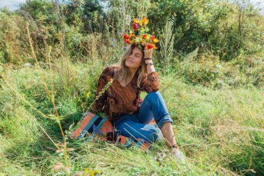 Güzel, mutlu bir kadının portresi, çimlerin üzerinde oturuyor ve viburum dalını tutuyor.