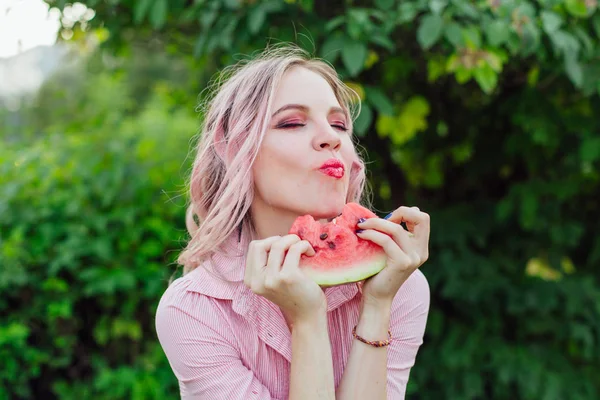 Beautiful young woman with pink hair enjoying watermelon — Stock Photo, Image