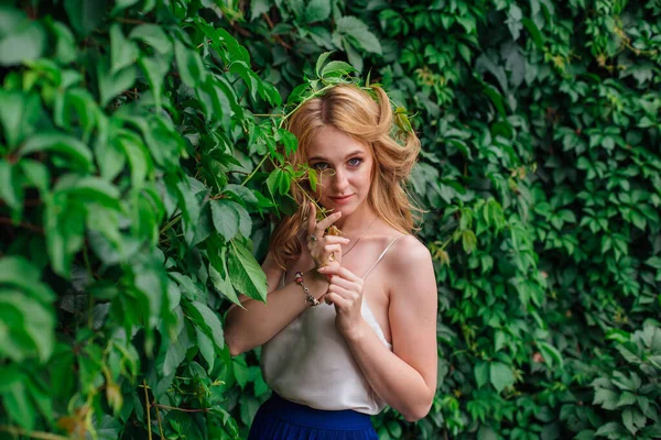 Retrato de uma jovem mulher bonita, de pé ao lado da parede de folhas de uva selvagem . — Fotografia de Stock