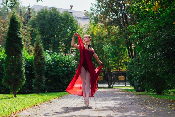 Kvinna ballerina i röd balett klänning dans i pointe skor i höstparken. — Stockfoto