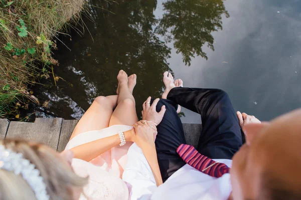 Wedding couple's feet sitting on the wooden bridge. — Zdjęcie stockowe