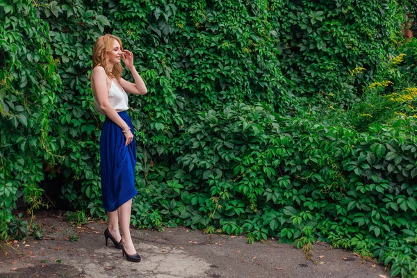 Ritratto di una giovane bella donna, in piedi accanto al muro di foglie di uva selvatica . — Foto Stock