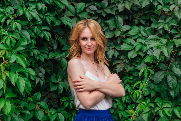 Retrato de uma jovem mulher bonita, de pé ao lado da parede de folhas de uva selvagem . — Fotografia de Stock