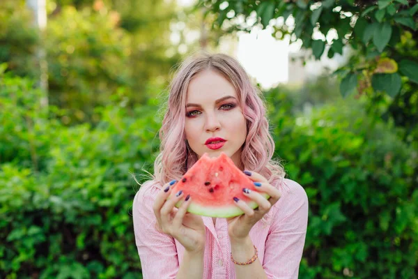 Mooie jonge vrouw met roze haren genieten van watermeloen — Stockfoto