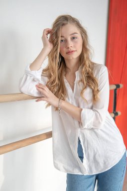 Bale makinesinde genç ve güzel bir kadın koreografın portresi. Sakin ve rahat kadın bale makinesinin yanında duruyor.