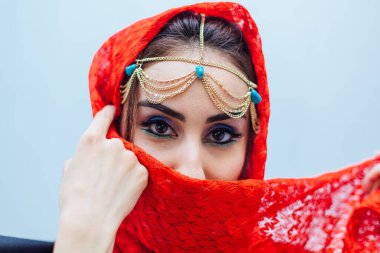 Parlak makyajlı ve kırmızı başörtüsü takan güzel bir doğu kadınının portresi..