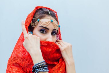 Parlak makyajlı ve kırmızı başörtüsü takan güzel bir doğu kadınının portresi..