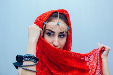 Parlak makyajlı ve kırmızı başörtüsü takan güzel bir doğu kadınının portresi..
