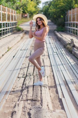 Sıcak yaz portresi, gün batımında eski paslı köprüde kovboy şapkası takan güzel bir kadın..