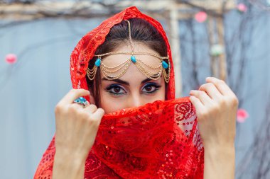 Parlak makyajlı ve kırmızı başörtüsü takan güzel bir doğu kadınının portresi..