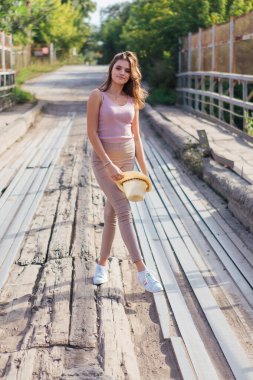 Sıcak yaz portresi, gün batımında eski paslı köprüde kovboy şapkası takan güzel bir kadın..