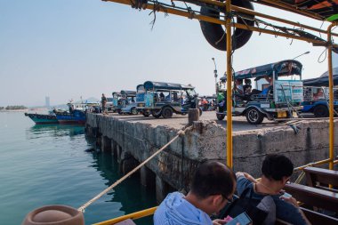 Sriracha, Chonburi, Thailand - February 15, 2018 : Three wheel moto Songthaew standing on a pier of a thai city Sriracha. View from ferry