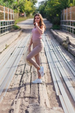 Sıcak yaz portresi, gün batımında eski paslı köprüde kovboy şapkası takan güzel bir kadın..