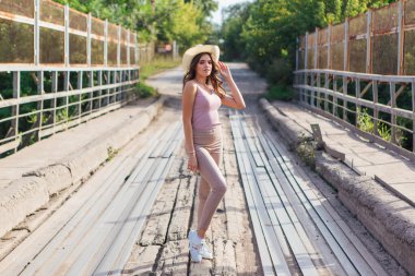 Sıcak yaz portresi, gün batımında eski paslı köprüde kovboy şapkası takan güzel bir kadın..