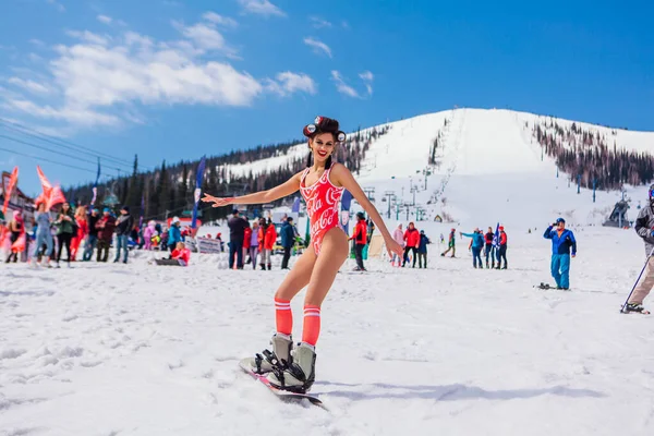 Sheregesh, región de Kemerovo, Rusia - 12 de abril de 2019: Joven mujer bonita feliz vestida en bikini montada en snowboard en la ladera de la nieve . — Foto de Stock
