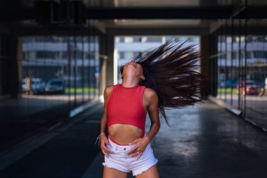 Genç, güzel esmer kadın dans ediyor ve saçlarını ayna kemerinde sallıyor..