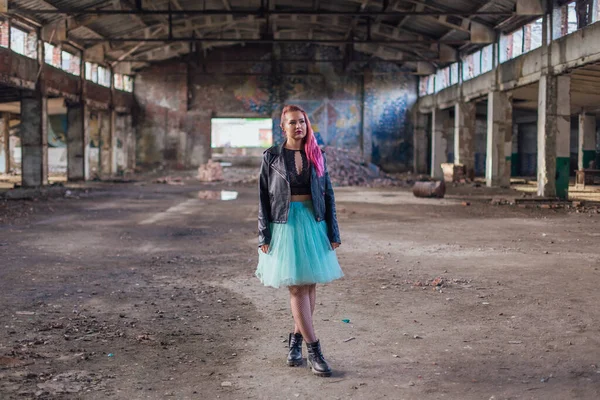 革のジャケットを着たピンク色の髪の少女の肖像画と廃墟に囲まれた崩壊した建物の中に立つ青いスカート — ストック写真